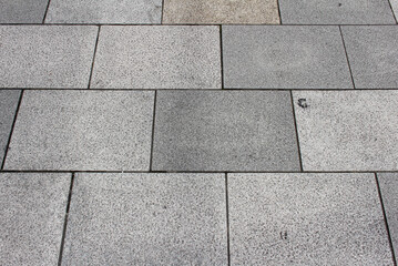 Texture of gray and beige square paving tile. Pattern of sidewalk tiles in the street. Concrete pavers close up background.