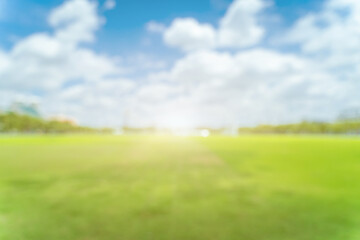 Beautiful blur green grass field background against summer sky with clouds on a bright sunny day