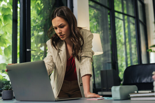Young businesswoman looking concerned at laptop in office