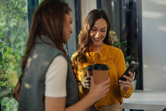 Gen z managers enjoying coffee break and looking at smartphone