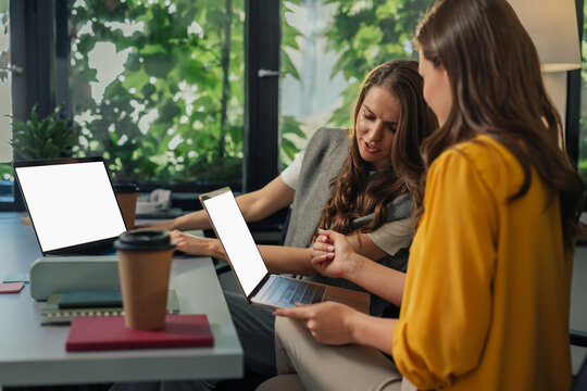Two gen z colleagues discussing over a laptop in a modern office