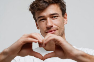 Man showing heart symbol with hands on white studio background
