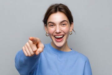Young woman pointing at camera with cheerful expression