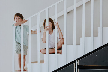 Obraz premium Two playful children enjoying their time on a staircase, showcasing joy and innocence, with bright colors and a minimalist background.