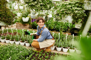 In lush greenhouse, young woman joyfully cultivates vibrant plants with care