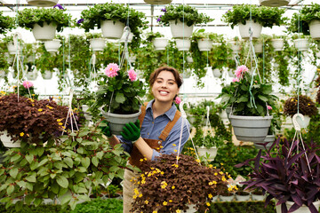 Joyful gardener tends vibrant plants in a lush, blooming greenhouse