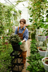 Young woman tending to vibrant plants in a sunlit greenhouse with care
