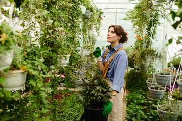 Young woman cultivates her passion for plants in a vibrant greenhouse filled with life