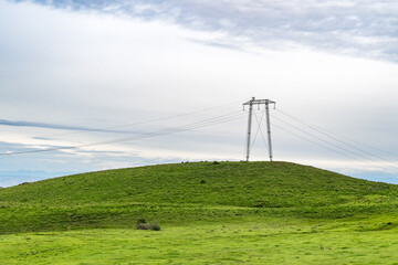 Metal power transmission line pole on green hill in Chui valley of Kyrgyzstan. Nature and energy.