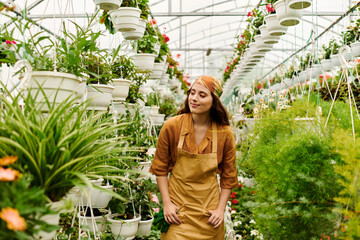 Young woman cultivates vibrant plants in a flourishing greenhouse oasis