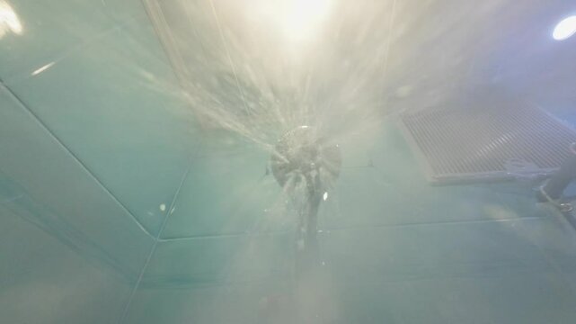 The shower turns on, the water flows to the camera.	
