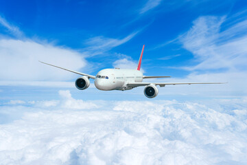 Obraz premium Airplane in the flight, travel background with airplane flying in the blue sky over the cloudscape. Flying airplane with blank livery