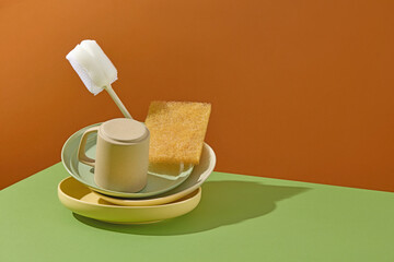 Similar concept to image 19 with brush and sponge placed into teacups. Creative and colorful still life for kitchen cleaning theme. Copy space