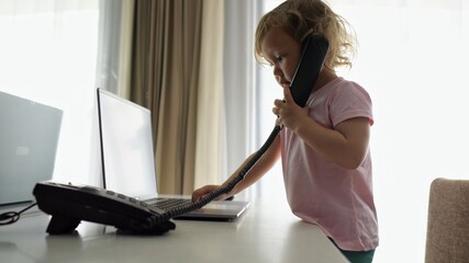 Preschooler girl picks up landline phone and pretends to talk