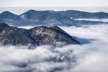 winter mountain landscape with snow, fog and cloud covered areas