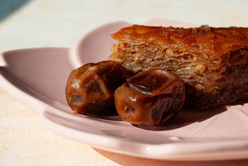 Traditional Turkish baklava dessert with dates, elegantly served on a pink plate.