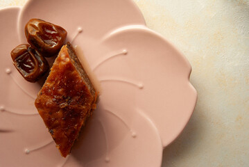 Traditional Turkish baklava dessert with dates, elegantly served on a pink plate.
