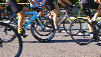 A close-up shot of a group of cyclists riding their bicycles down a street, showcasing their active lifestyle and passion for cycling.