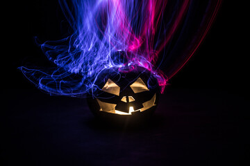Halloween concept. Creepy silhouette in the dark corridor with pumpkin head. Toned light with fog on background.