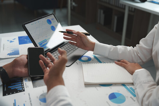 Business colleagues discussing financial charts and data on tablet and printed reports
