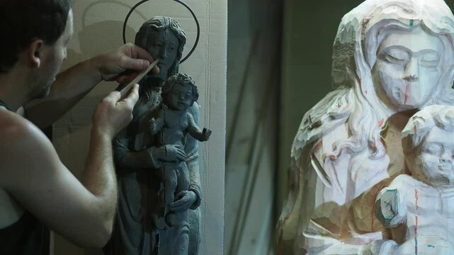 large wooden Virgin Mary and Jesus Christ baby statue using chisel, focused on traditional woodworking techniques inside workshop, highlighting manual skill, slow mo