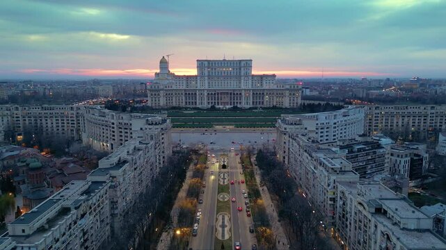 Aerial drone footage of the house of the people in Bucharest. High angle golden hour shot of the  Parliament building in the capital or Romania. Massive governmental structure seen from the air.
