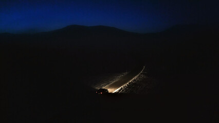 Dark, starless sky contrasts with the distant mountain range, creating a sense of solitude and...