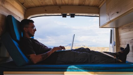 Freelancer working remotely on laptop in camper van at gorafe, spain
