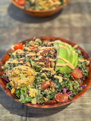 Rainbow bowl - hawaiian food for lunch made of kale salad with red cabbage and green onion. Topped with avocado, grape tomato, almonds and hummus