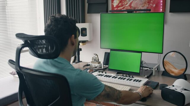 Music producer types at desk surrounded by audio tools and VR headset