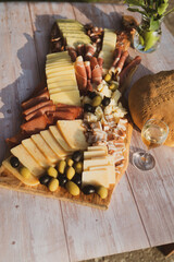 Catering on a wooden board on a rustic table, meat, olives, cheese, and a drink as an appetizer