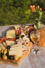 Catering on a wooden board on a rustic table, meat, olives, cheese, and a drink as an appetizer