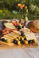 Catering on a wooden board on a rustic table, meat, olives, cheese, and a drink as an appetizer
