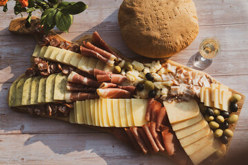 Catering on a wooden board on a rustic table, meat, olives, cheese, and a drink as an appetizer