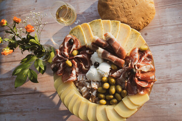Catering on a wooden board on a rustic table, meat, olives, cheese, and a drink as an appetizer