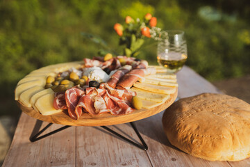 Catering on a wooden board on a rustic table, meat, olives, cheese, and a drink as an appetizer