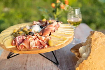 Catering on a wooden board on a rustic table, meat, olives, cheese, and a drink as an appetizer