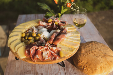 Catering on a wooden board on a rustic table, meat, olives, cheese, and a drink as an appetizer
