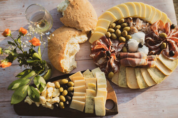 Catering on a wooden board on a rustic table, meat, olives, cheese, and a drink as an appetizer