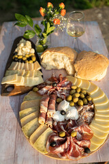 Catering on a wooden board on a rustic table, meat, olives, cheese, and a drink as an appetizer
