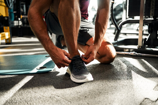 Man Tying Running Shoes in Gym for Workout