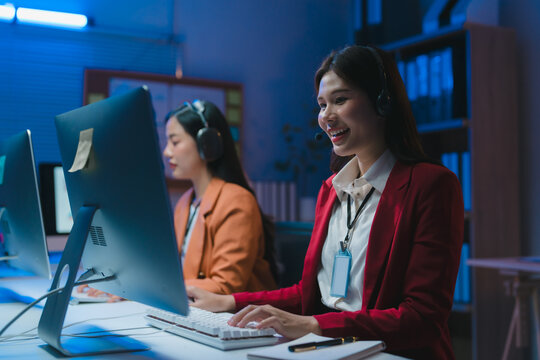 Asian telemarketer woman smiling and working late night shift in office - Powered by Adobe