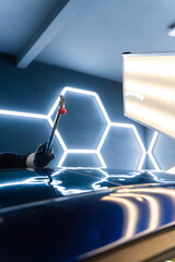 Paintless dent repair tool works from inside the car panel. The technician uses a leverage bar to...