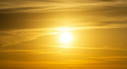 Obraz premium Golden hour sunset with soft, hazy clouds surrounding a bright sun