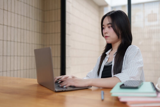 Young asian freelancer woman working on laptop at home office