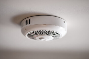 White smoke detector is mounted on ceiling, providing safety and security in home environment. device is essential for detecting smoke and alerting occupants in case of fire
