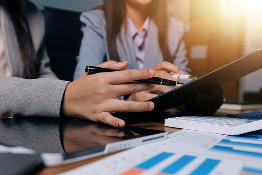 Group of confident business people point to graphs and charts to analyze market data, balance sheet, account, net profit to plan new sales strategies to increase production capacity.