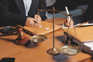 Attractive young lawyer in office Business woman and lawyers discussing contract papers with brass scale on wooden desk in office. Law, legal services, advice, Justice and real estate concept.