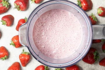 Strawberry milkshake freshly prepared in a blender bowl, top view