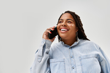 Bright smile of a confident African American woman in denim outfit in studio setting